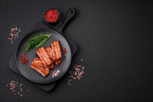 stock image Grilled fresh juicy ribs with salt, spices and herbs on a dark concrete background