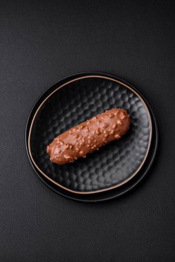 Lezzetli taze pasta ya da koyu beton arka planda çikolata ve fındıklı profiterol.