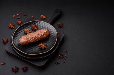 Lezzetli taze pasta ya da koyu beton arka planda çikolata ve fındıklı profiterol.