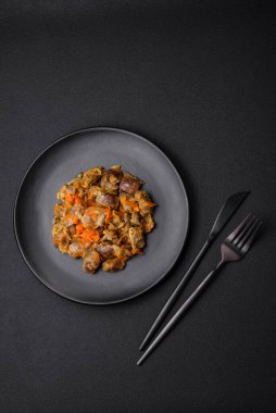 Havuçlu ve domatesli lezzetli güveçte tavuk taşakları koyu beton arka planda.