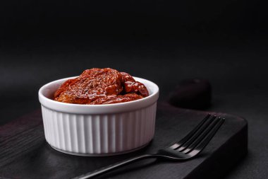 Lezzetli güneş, koyu beton arka planda beyaz bir seramik kasede yağda kurutulmuş domatesler.