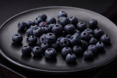 Taze yaban mersinleri ve siyah beton bir arka plan. Mevsimlik böğürtlen toplamak