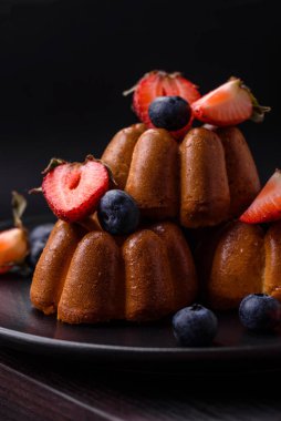 Lezzetli kekler ya da kuru üzüm ve fındıklı kekler, seramik tabakta çilek ve yaban mersini desenli beton masa