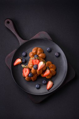 Lezzetli kekler ya da kuru üzüm ve fındıklı kekler, seramik tabakta çilek ve yaban mersini desenli beton masa