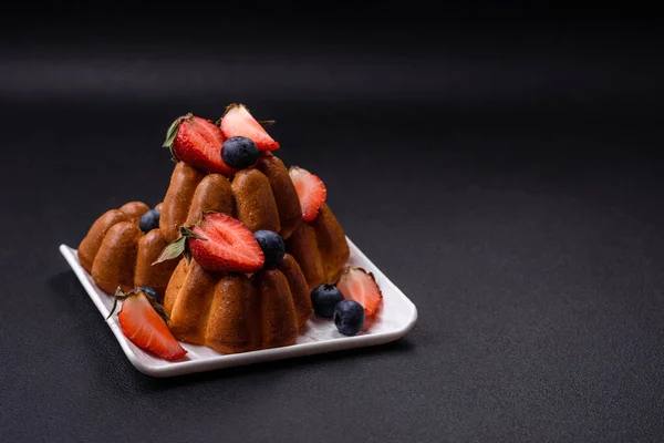 stock image Delicious cupcakes or muffins with raisins and nuts, strawberries and blueberries on a ceramic plate on a textured concrete table