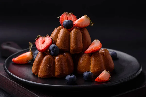 Stock image Delicious cupcakes or muffins with raisins and nuts, strawberries and blueberries on a ceramic plate on a textured concrete table