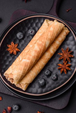 Lezzetli gevrek gofretler, koyu beton arka planda fındıkla dolu kremalı.