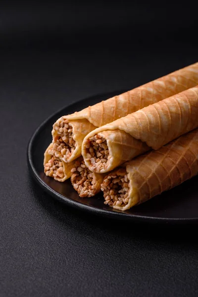 stock image Delicious crispy wafer rolls with cream filling with nuts on a dark concrete background