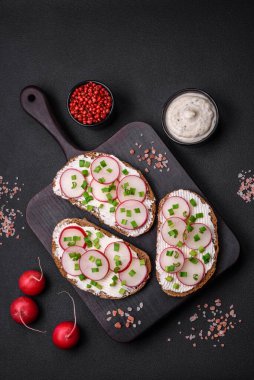 Lezzetli sandviç ya da krem peynirli turp ve koyu betondan yapılmış yeşil soğanlı bruschetta.