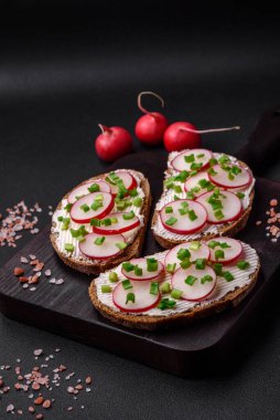 Lezzetli sandviç ya da krem peynirli turp ve koyu betondan yapılmış yeşil soğanlı bruschetta.
