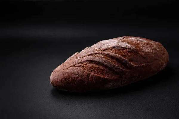 濃いコンクリートの背景に穀物やスパイスとおいしい新鮮なシャキッとした茶色のパン — ストック写真
