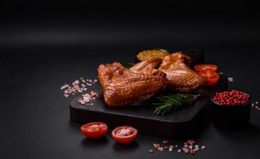 Lezzetli ızgara tavuk kanatları. Baharatlar ve otlarla birlikte. Koyu beton bir arka plan.