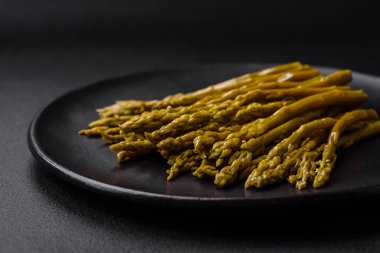 Siyah seramik tabakta koyu beton arka planda lezzetli konserve kuşkonmaz.