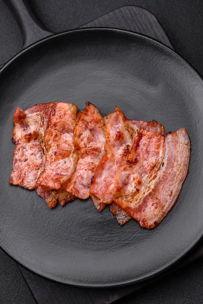 Läckra Färska Stekta Bacon Ränder Med Kryddor Mörk Betong Bakgrund — Stockfoto