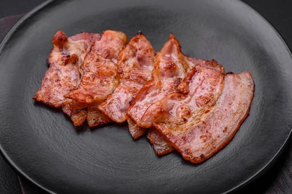 Läckra Färska Stekta Bacon Ränder Med Kryddor Mörk Betong Bakgrund — Stockfoto