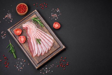 Tuz ve baharatlı leziz taze pancetta koyu beton arka planda ince dilimler halinde kesilmiş.