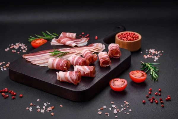 stock image Delicious fresh pancetta with salt and spices cut into thin slices on a dark concrete background