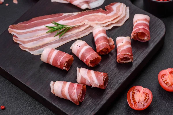 stock image Delicious fresh pancetta with salt and spices cut into thin slices on a dark concrete background