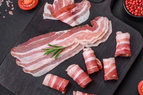 Stock image Delicious fresh pancetta with salt and spices cut into thin slices on a dark concrete background