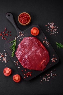 Taze çiğ et, tuz, baharat ve çimento arka planda bitkiler.