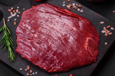 Taze çiğ et, tuz, baharat ve çimento arka planda bitkiler.