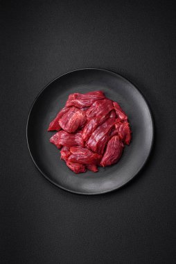 Taze çiğ et, tuz, baharat ve çimento arka planda bitkiler.