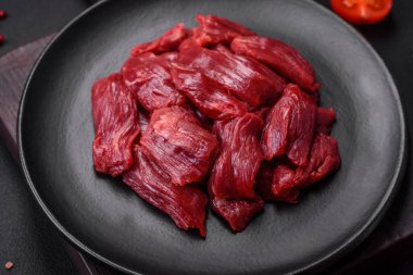 Taze çiğ et, tuz, baharat ve çimento arka planda bitkiler.