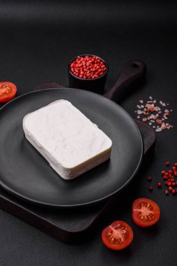 Lezzetli, dikdörtgen şekilli, koyu beton arka planda baharat ve sebzeli feta peyniri.