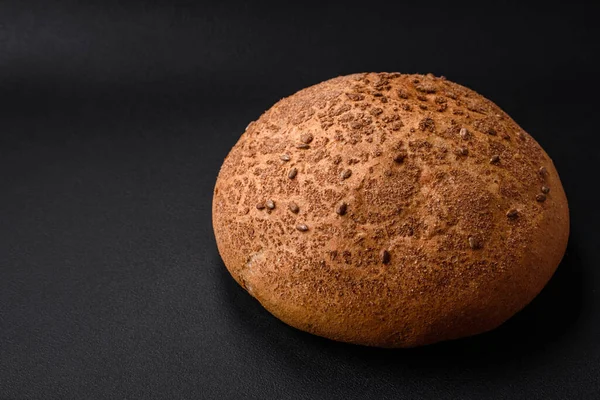 stock image Fresh crispy brown bread with sesame seeds and spices on a dark concrete background