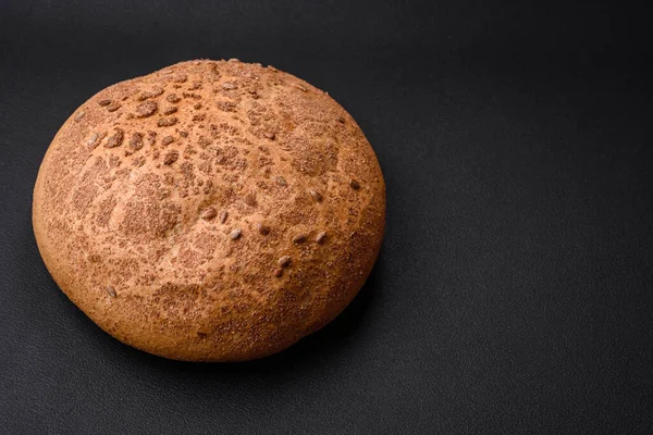 stock image Fresh crispy brown bread with sesame seeds and spices on a dark concrete background