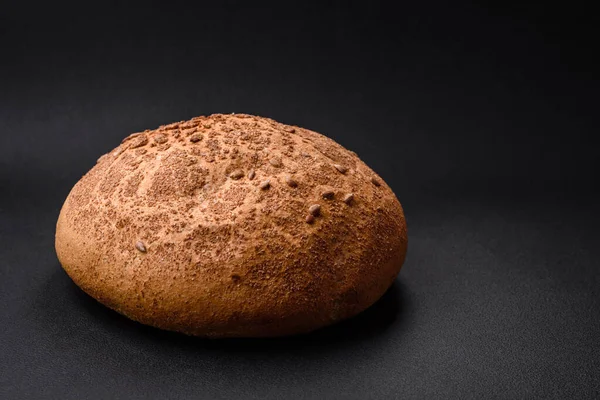 薄暗いコンクリートの背景にゴマやスパイスと新鮮なシャキッとした茶色のパン — ストック写真