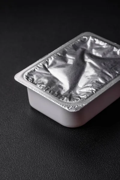 矩形塑料盒 装有酸奶或奶酪 密封在深色混凝土衬底上有箔盖 — 图库照片