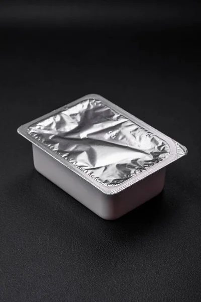 矩形塑料盒 装有酸奶或奶酪 密封在深色混凝土衬底上有箔盖 — 图库照片