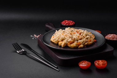 Tavuk ve sebzeli lezzetli erişte mi yoksa siyah seramik tabakta koyu beton arka planda udon mu?