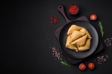 Eti, tuzu ve baharatı koyu beton arka planda üçgen şeklinde leziz krepler.