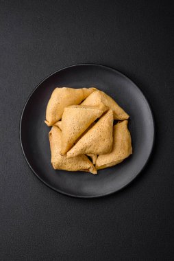 Eti, tuzu ve baharatı koyu beton arka planda üçgen şeklinde leziz krepler.