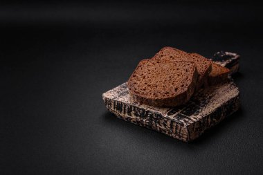 Koyu beton arka planda tahıl ve tohumlarla bir somun taze gevrek kahverengi ekmek.