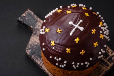 Yeni pişmiş Paskalya pastası ya da içinde çikolata kaplama ve kuru üzümler olan panettone koyu beton arka planda ahşap bir kesim tahtasının üzerinde.