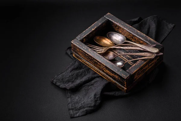 stock image Vintage rectangular shabby wooden box with spoons and forks on a dark concrete background