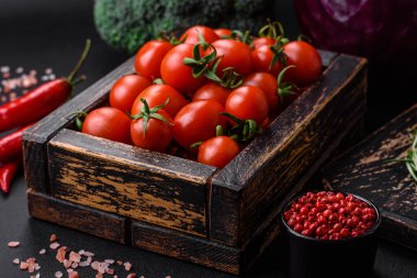 Koyu beton arka planda ahşap bir kutuda taze kırmızı kiraz domatesleri.