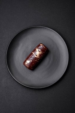 Çikolatayla kaplanmış lezzetli tatlı peynir ve koyu beton arka planda seramik tabakta fındık.