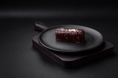 Çikolatayla kaplanmış lezzetli tatlı peynir ve koyu beton arka planda seramik tabakta fındık.