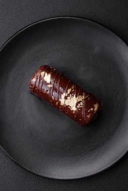 Çikolatayla kaplanmış lezzetli tatlı peynir ve koyu beton arka planda seramik tabakta fındık.