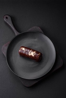 Çikolatayla kaplanmış lezzetli tatlı peynir ve koyu beton arka planda seramik tabakta fındık.