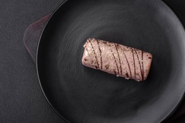 Çikolatayla kaplanmış lezzetli tatlı peynir ve koyu beton arka planda seramik tabakta fındık.