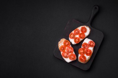 Koyu beton arka planda peynirli ve kiraz domatesli lezzetli kızarmış ekmek.