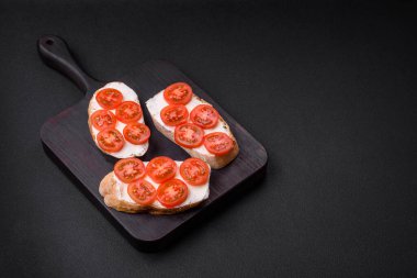 Koyu beton arka planda peynirli ve kiraz domatesli lezzetli kızarmış ekmek.