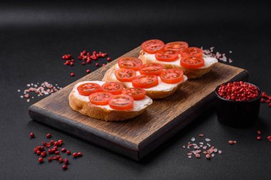 Koyu beton arka planda peynirli ve kiraz domatesli lezzetli kızarmış ekmek.