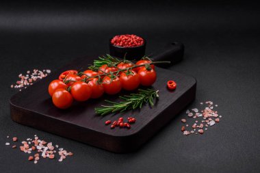 Koyu beton bir arka planda ince bir dal üzerinde lezzetli taze kiraz domatesleri. Vejetaryen yemekleri.