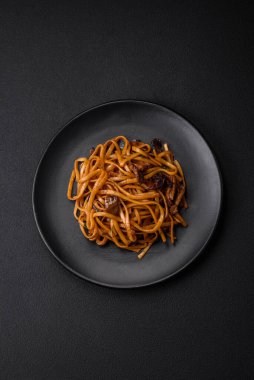 Lezzetli erişte ya da mantarlı udon, tuz, baharat ve otlar koyu beton bir zeminde seramik bir tabakta.